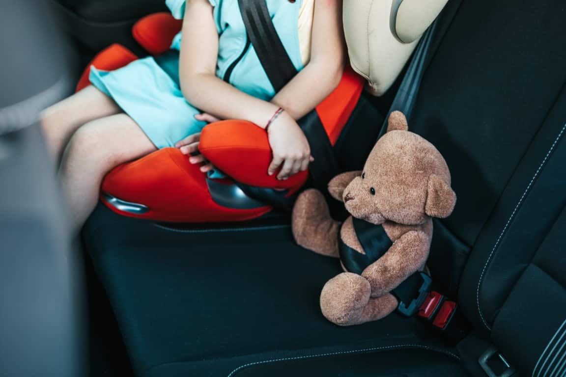 Enfant dans siège auto mettant sa ceinture